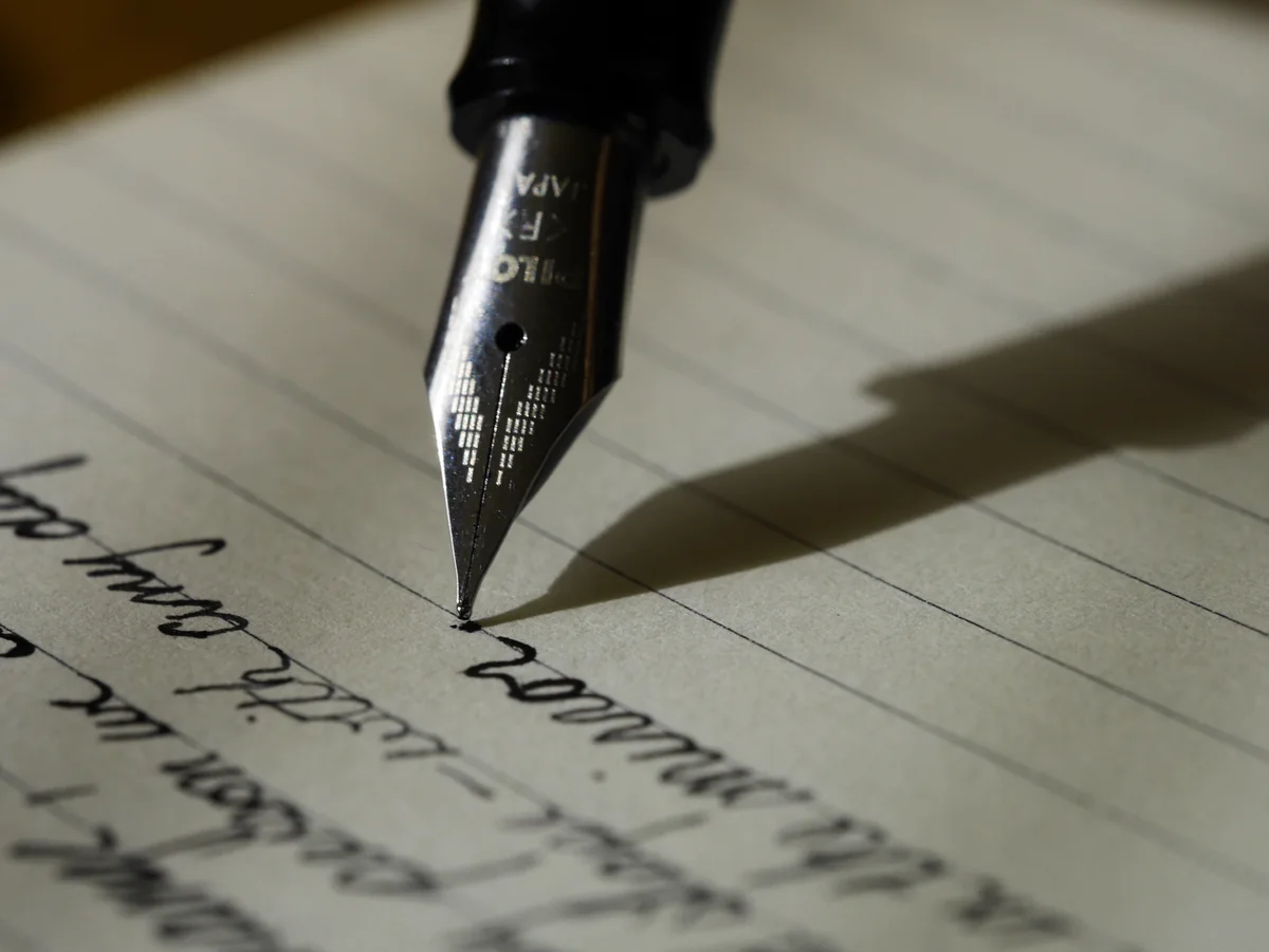 Detalle de una pluma escribiendo sobre papel. Fotografía ilustrativa de documentación, no de un formulario oficial de Jujuy.